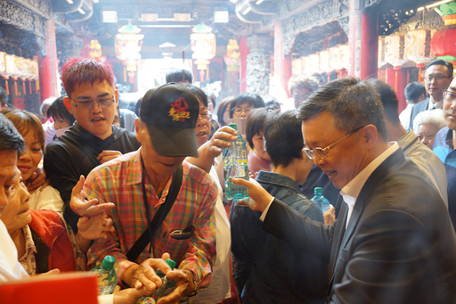 臺鹽董事長陳啓昱(右)發送「台鹽海洋鹼性離子水」給信眾,吸引人潮索取。