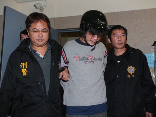 The suspect (center) is escorted by police officers when being transferred Monday.