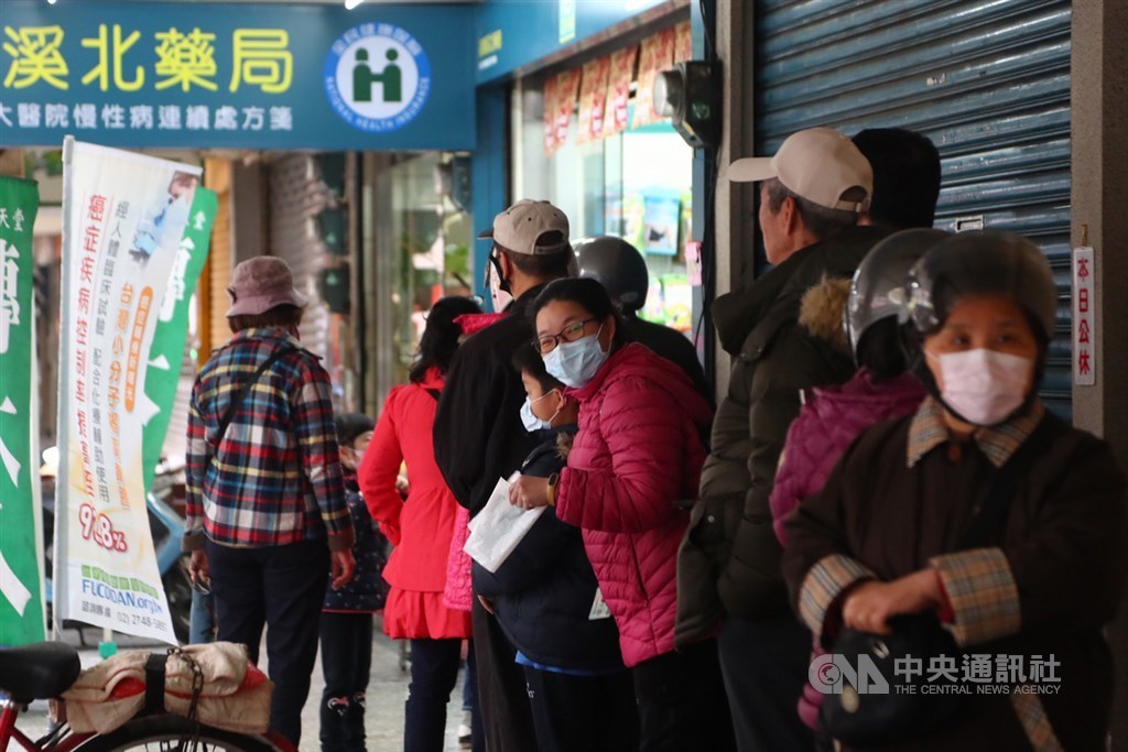 People lining up outside a pharmacy in New Taipei to purchase face masks on the first day of the rationing system.
