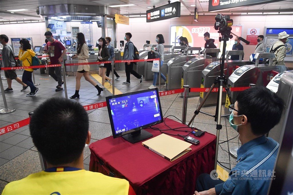 MRT employees look at an infrared thermometer at Taipei Main Station.