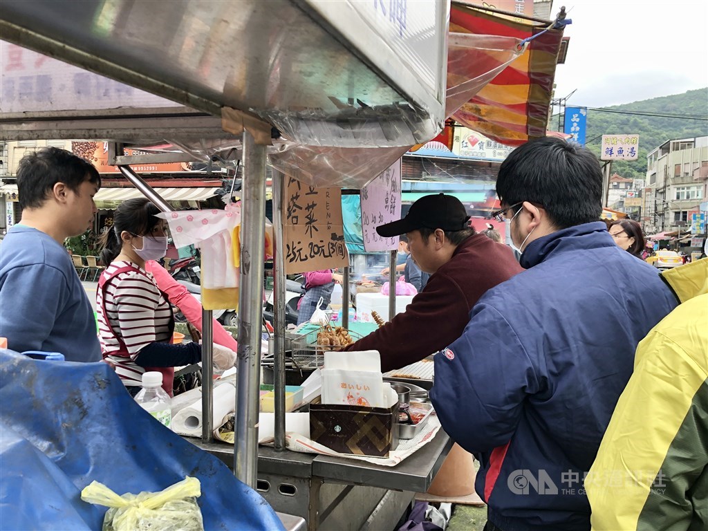 A line of people buy grilled food from a vendor in Yilan