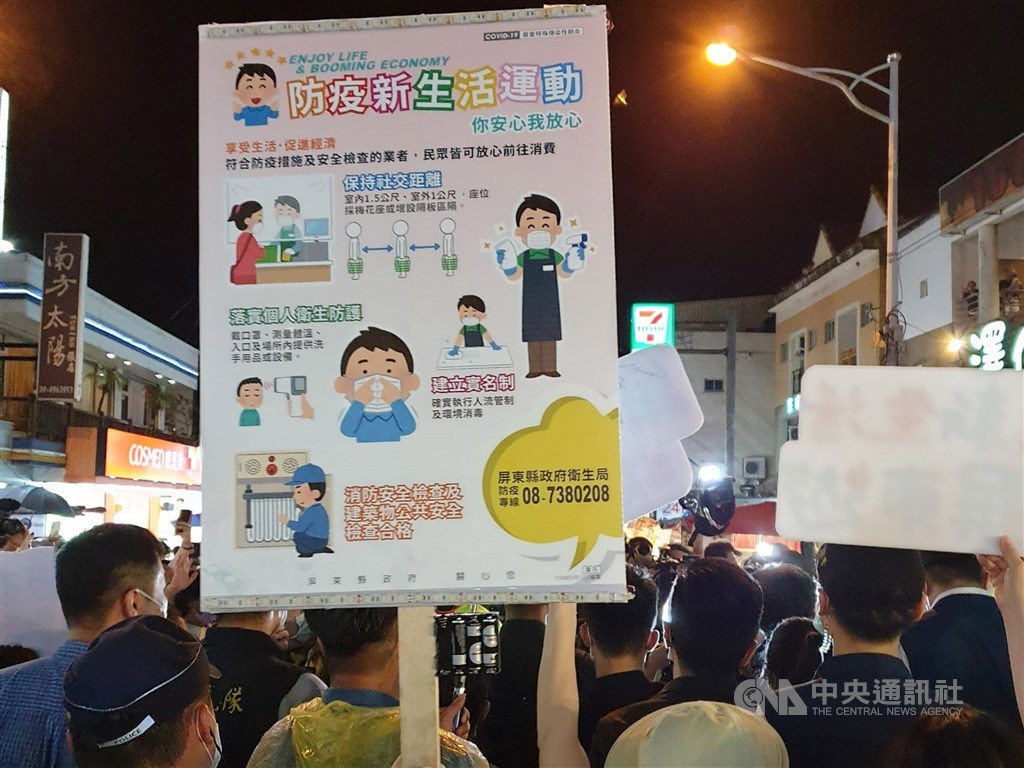 A sign reminding visitors to Kenting to wear a face mask and follow social distancing rules is pictured Saturday night.