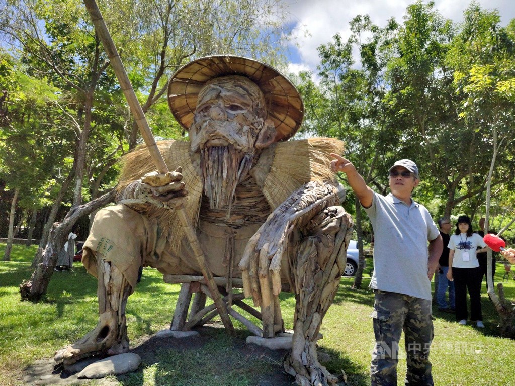 Amis tribe artist Talaluki poses next to his work created with driftwood.