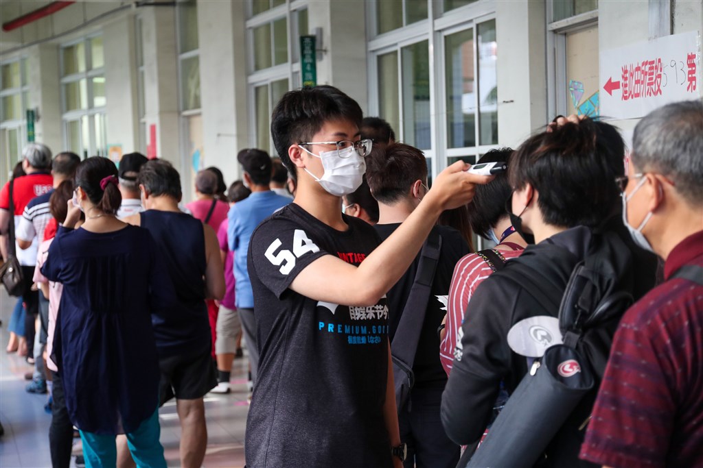 People waiting in line at a polling station have their temperatures taken amid the COVID-19 coronavirus pandemic.