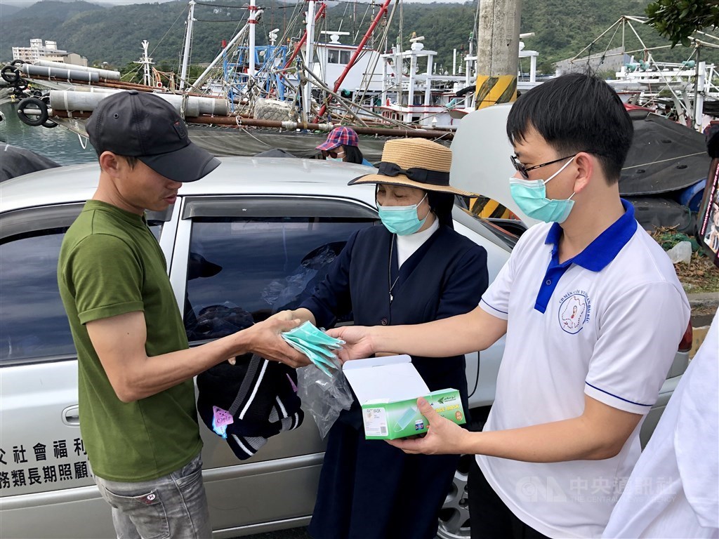 Father Gioan Tran Van Thiet (right) gives a migrant fisher masks in Yilan