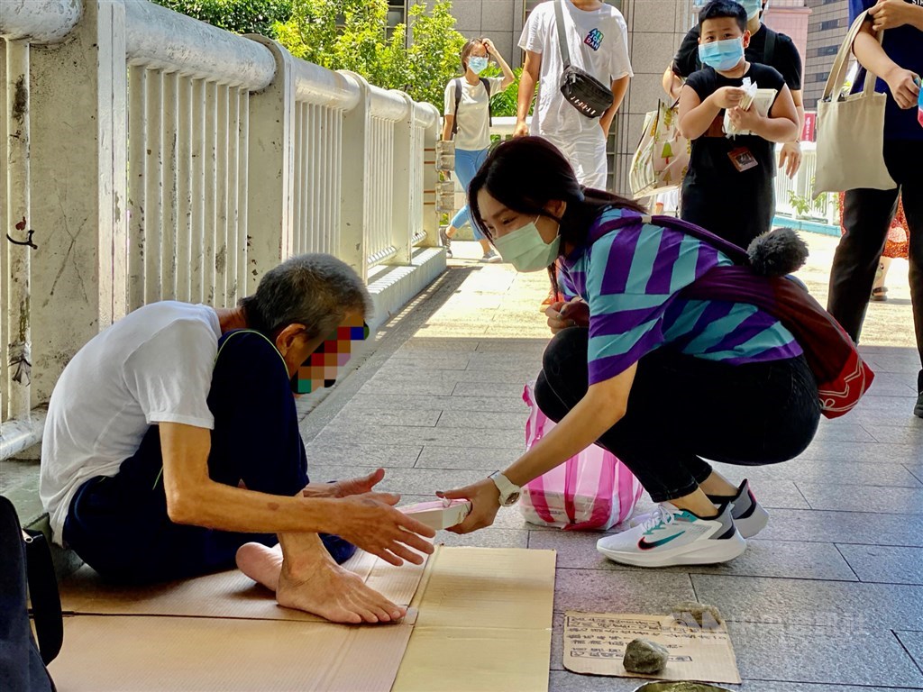 A Vietnamese student hands out a packed lunch box to a homeless man near Taipei Main Station on Saturday