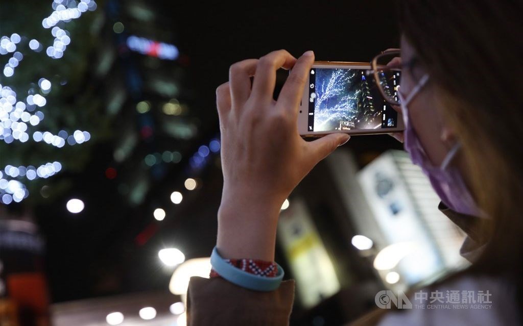 A passerby takes a photo of celebratory messages on the Taipei 101 building . CNA photo Dec. 9, 2020