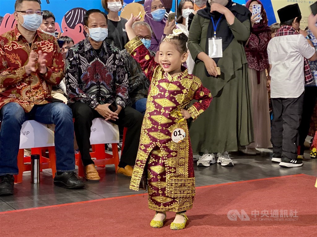 A young girl waves to the audience at
