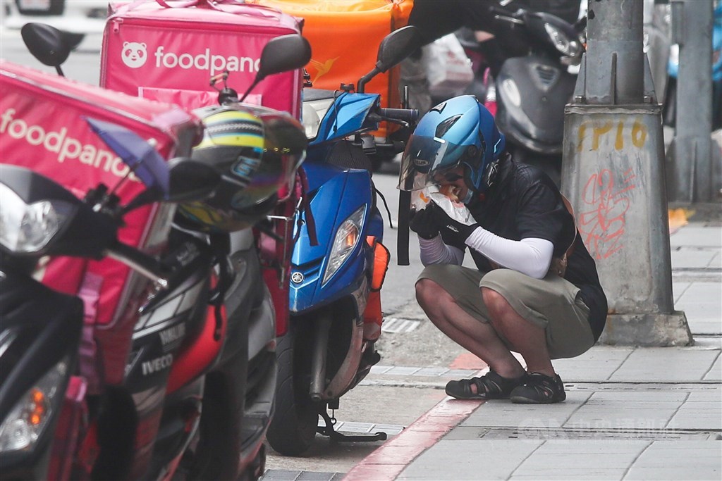 A food delivery worker have a quick meal on the roadside. CNA photo May 26, 2021