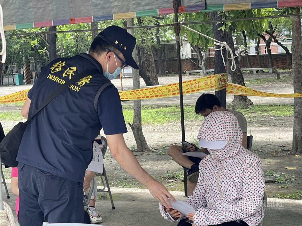 An immigration officers hands a paper form to a woman in Kaohsiung. Photo courtesy of the NIA