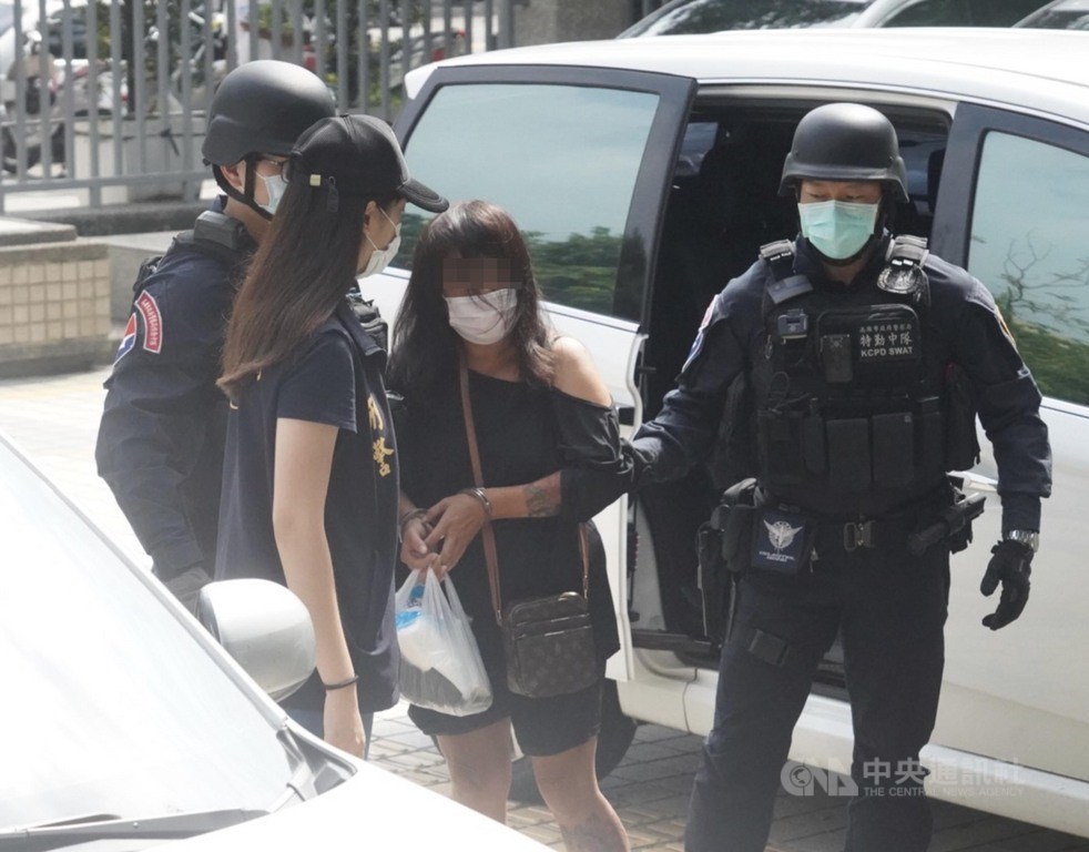 The 51-year-old Huang (second right) is brought in by the police for question Friday. CNA photo Oct. 17, 2021