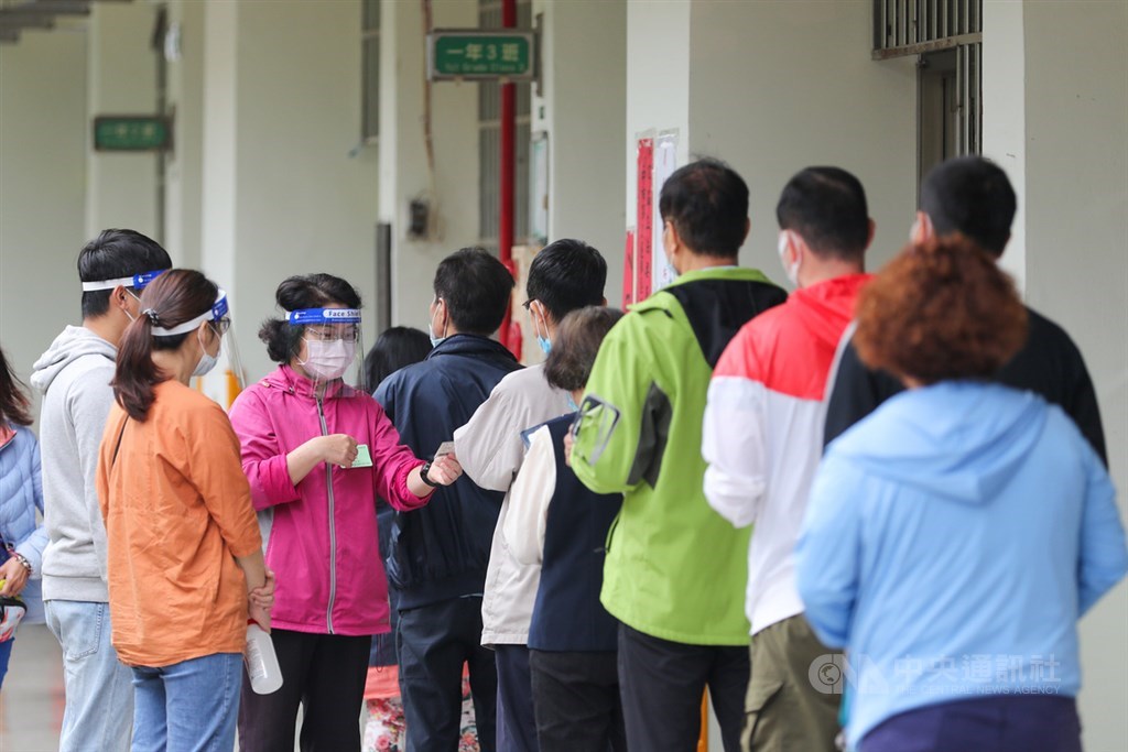Voters wait in a queue outside a polling station in Taichung Saturday. CNA photo Oct. 23, 2021