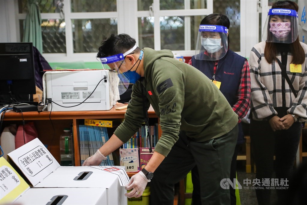 Electoral officers at a polling station in Taipei for the Dec. 18 referendum wear face shields and gloves to guard against COVID-19.