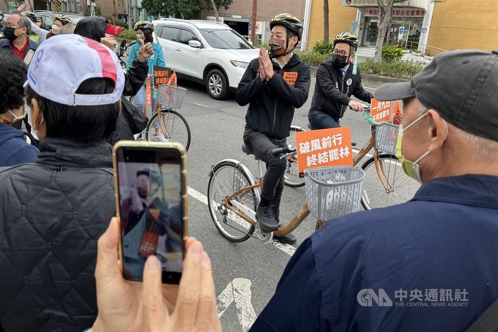 Incumbent independent Legislator Freddy Lim rides a bike with his entourage while campaigning in Taipei