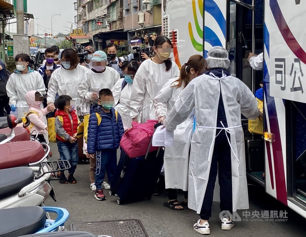 Parents and their children who go to the same kindergarten with a boy confirmed to have COVID-19 in Kaohsiung get on a bus that will take them to quarantine facilities Thursday. CNA photo Jan. 20, 2022