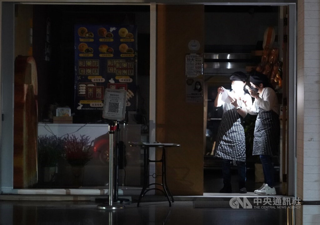Workers of a bakery in Kaohsiung use mobile phone for light during the power outage on March 3. CNA file photo