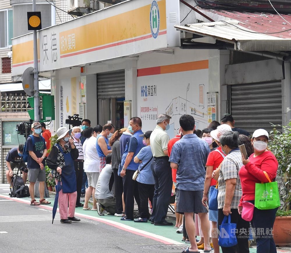 People wait in line outside a Taipei pharmacy as the government launched its COVID-19 rapid test kit rationing scheme on Thursday. CNA photo April 28, 2022