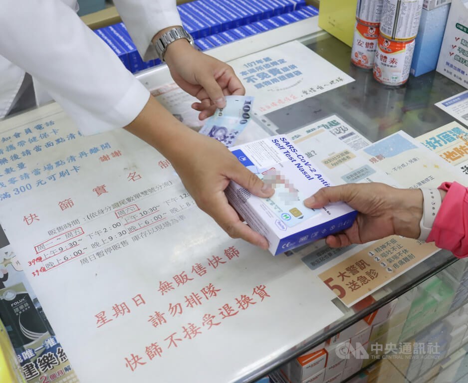 A pharmacist hands over a pack of rapid test kits sold through the government