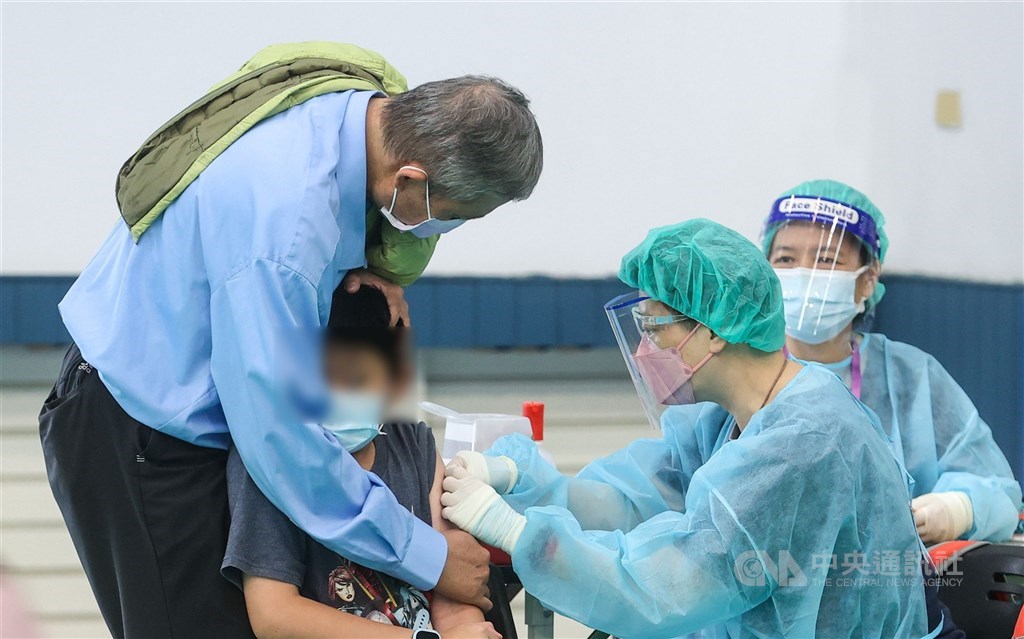 A man holds a child when he was given a dose of the Pfizer-BioNTech COVID-19 vaccine at a school in Taipei Thursday. CNA photo May 27, 2022