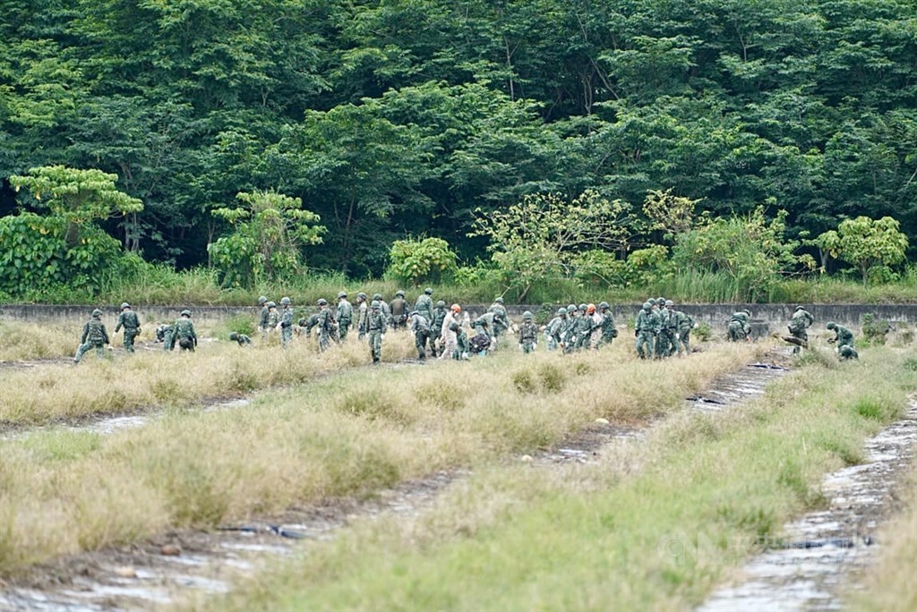 Soldiers check through the crash site -- a farm field in Kaohsiung