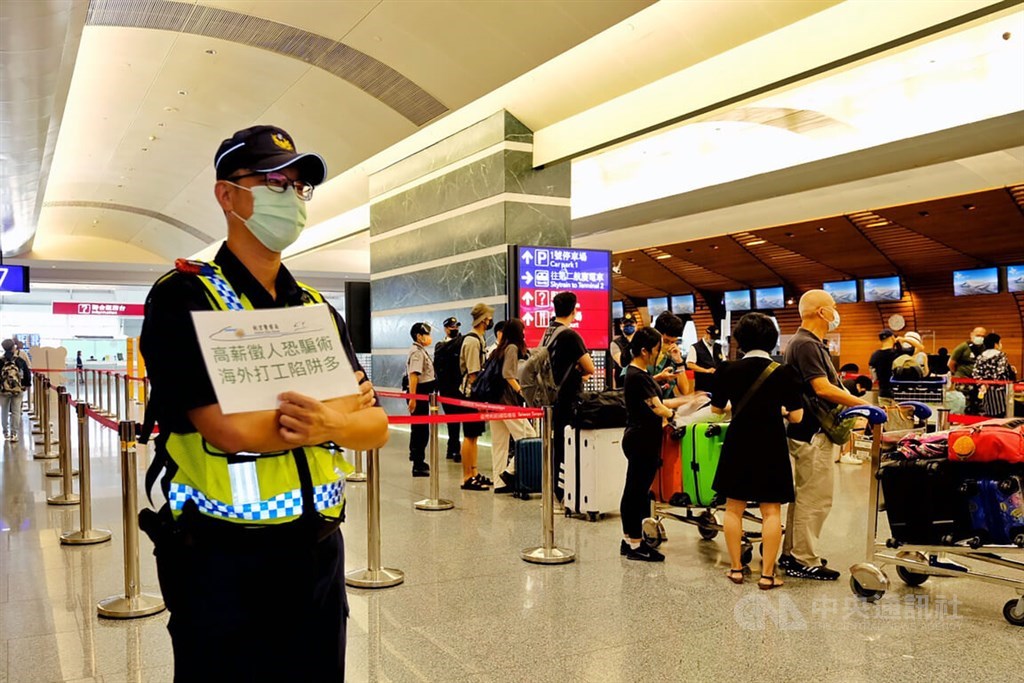 A policeman holds a sign warning passengers about job scams at Taiwan Taoyuan International Airport on Thursday. CNA photo Aug. 18, 2022