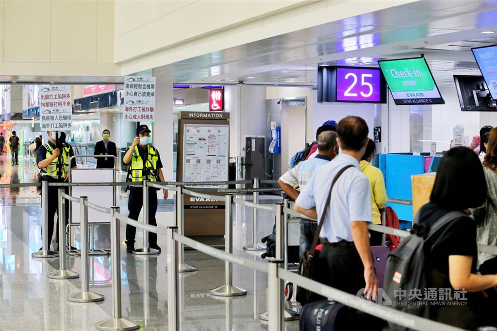 Policemen hold signs to warn passengers planning to travel to Cambodia about job scams reportedly linked to the Southeast Asian country, at Taiwan Taoyuan International Airport in early August.