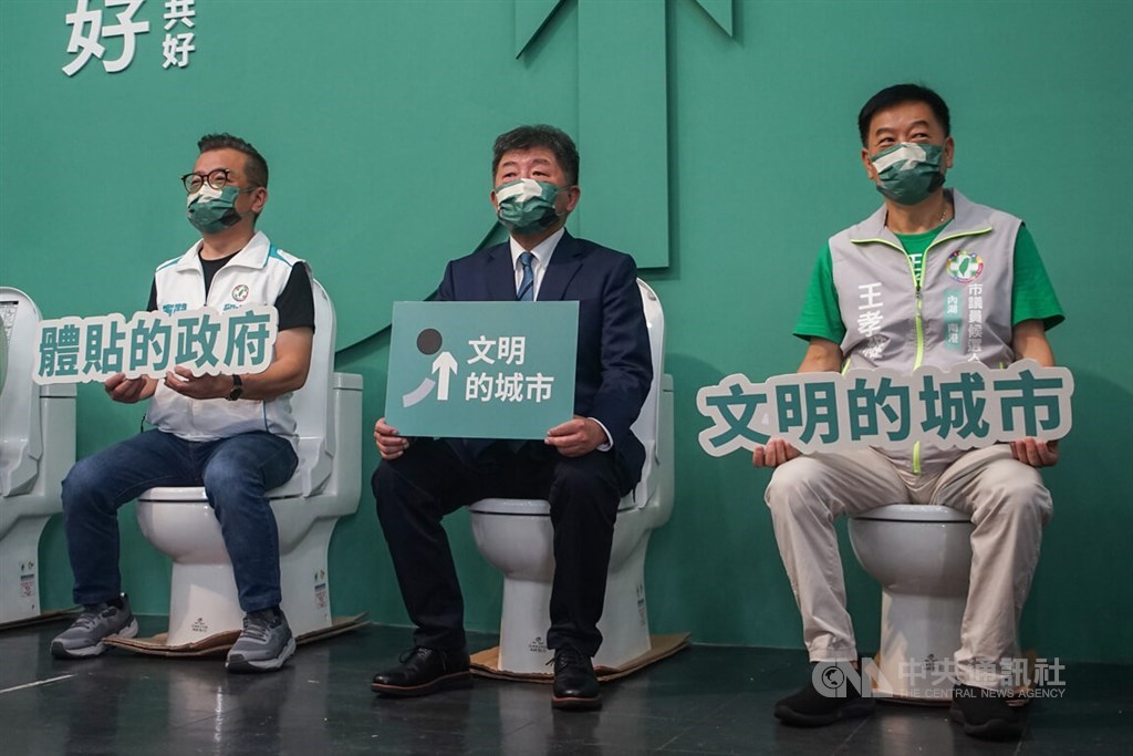 DPP Taipei mayor candidate Chen Shih-chung (center) sits on a toilet and holds a sign saying "civilized city" during a campaign event on Saturday. CNA photo Sept. 3, 2022