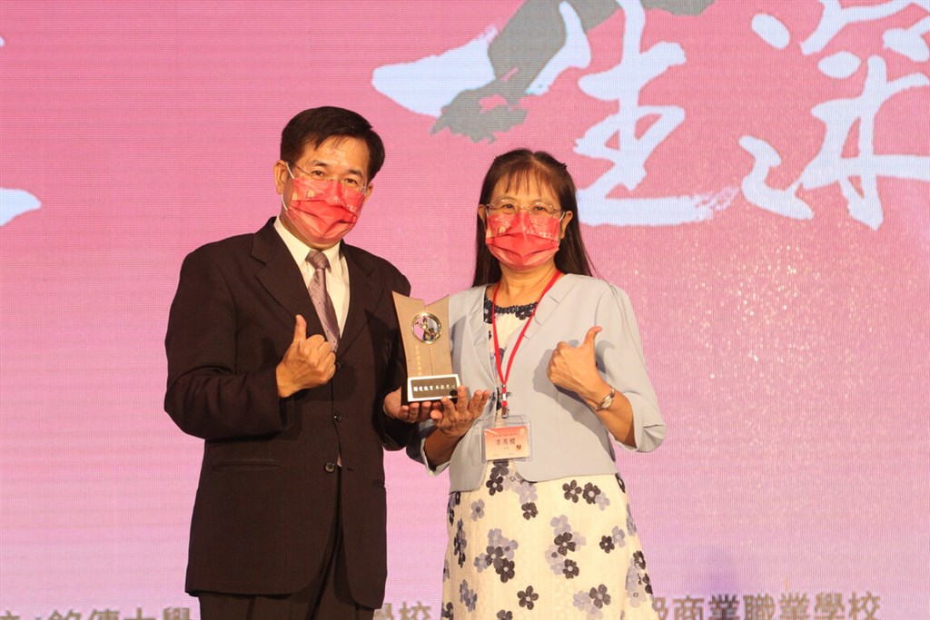 Minister of Education Pan Wen-chung (left) presents an excellent teacher award to Lee Hsiu-ying, principal of Fu Chuen Elementary School in Taichung, during Monday