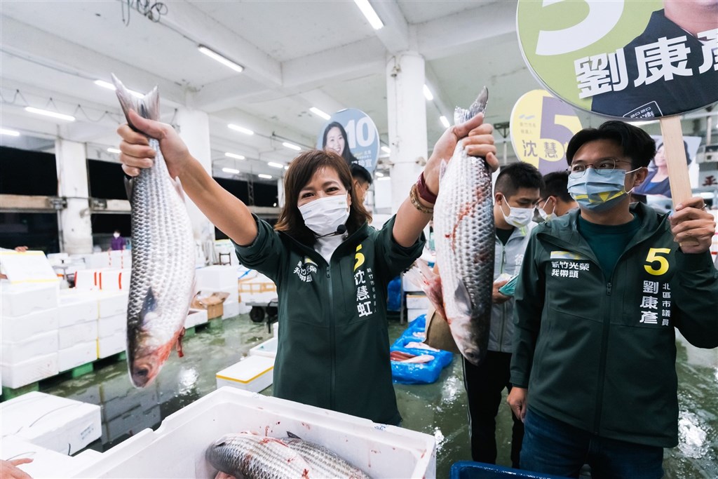 DPP candidate for Hsinchu mayor Shen Hui-hung (沈慧虹) holds up two fish during her visit to a local seafood market on Tuesday. Photo taken from Shen Hui-hung