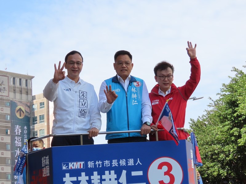 KMT candidate for Hsinchu mayor Lin Ken-jeng (林耕仁, center) stands in a campaign motorcar and raises three fingers -- representing his number in the election race -- accompanied by KMT Chairman Eric Chu (朱立倫, left) and KMT lawmaker Cheng Cheng-chien (鄭正鈐). CNA photo Nov. 15, 2022