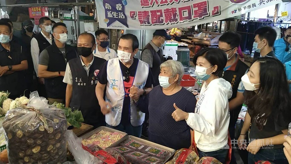 Former President Ma Ying-jeou (馬英九, in white vest) and KMT candidate for Chiayi County magistrate, Wang Yu-min (王育敏, in white jacket) pose with a supporter for photos when campaigning at a wet market in Chiayi