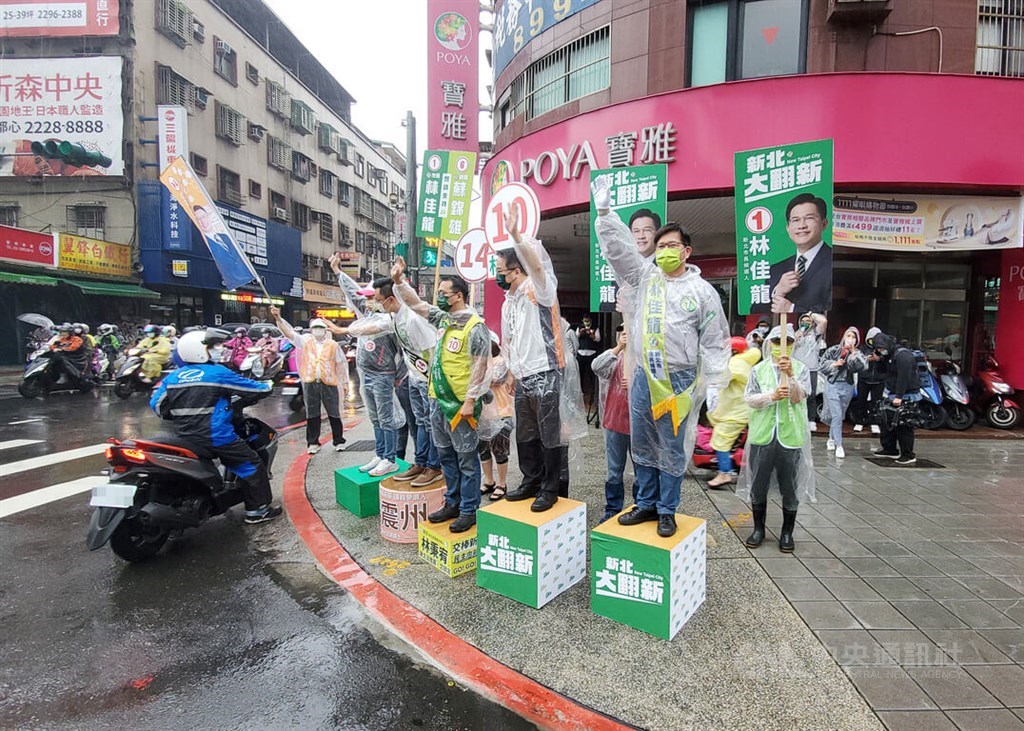 DPP New Taipei mayoral candidate Lin Chia-lung (林佳龍, front right) waves to commuters during the morning rush hour near Xingfu metro station in the city