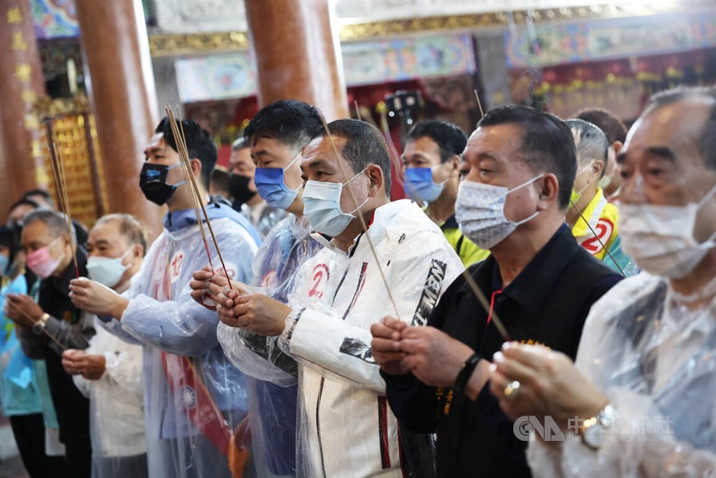 Incumbent New Taipei Mayor Hou Yu-ih (侯友宜, third right) of the KMT holds an incense stick as he prays at a Taoist temple in the city