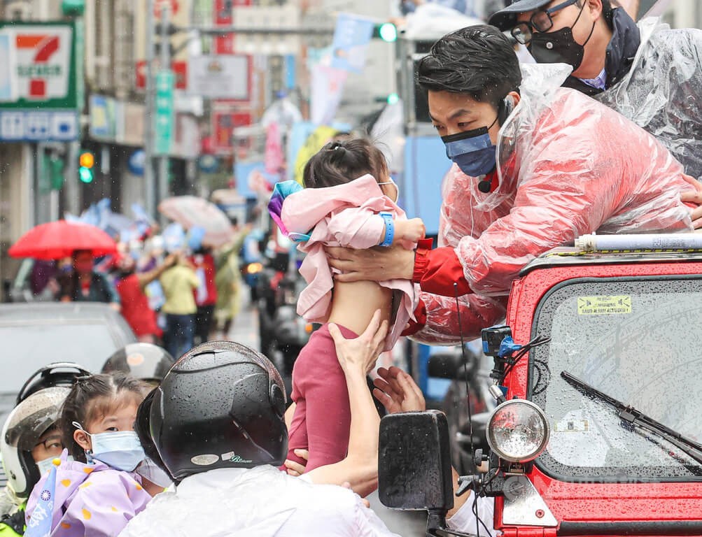 KMT Taipei mayoral candidate Chiang Wan-an (蔣萬安) picks up a young girl while greeting supporters during a motorcade campaign in Taipei on Thursday. CNA photo Nov. 24, 2022