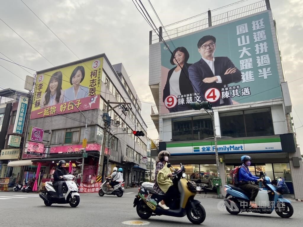 Scooters ride past two campaign billboards featuring candidates of the opposition Kuomintang (KMT) and the ruling Democratic Progressive Party (DPP) in Kaohsiung on Thursday. CNA photo Nov. 24, 2022