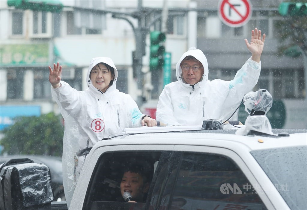 Independent Taipei mayoral candidate Huang Shan-shan (黃珊珊, left) and Taipei Mayor Ko Wen-je (柯文哲) wave from a campaign vehicle in the rain on Thursday. Huang is endorsed by the Taiwan People