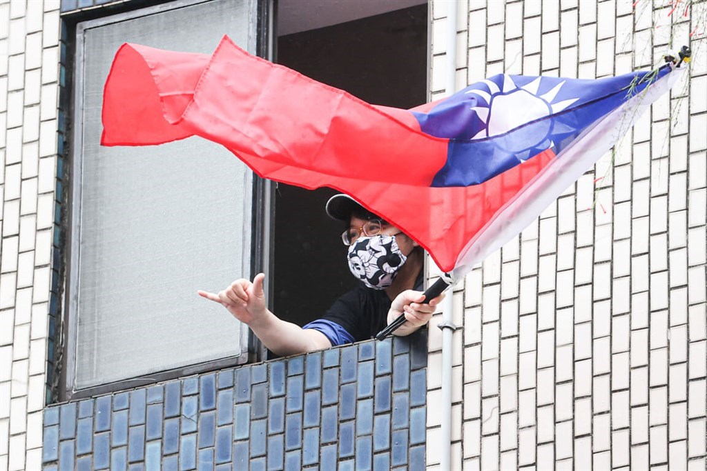 A man in Taipei waves a national flag of the Republic of China (Taiwan) as a campaign motorcade drove past his building. CNA photo Nov. 24, 2022