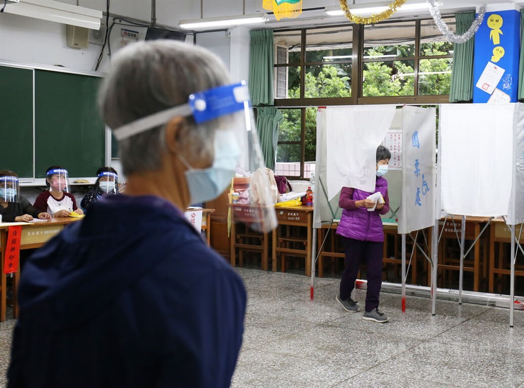 A voter (right) is seen at a polling station located at New Taipei Municipal Yulin Junior High School on Saturday. CNA photo Nov. 26, 2022