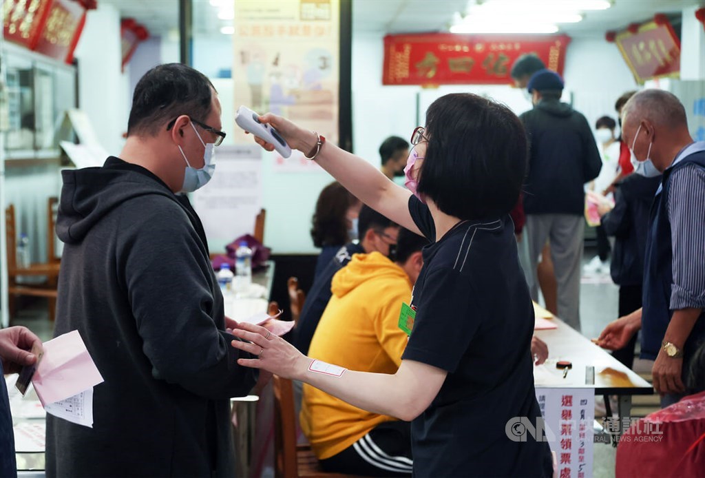 A polling station worker checks the temperature of a voter at the entrance on Saturday. CNA photo Nov. 26, 2022