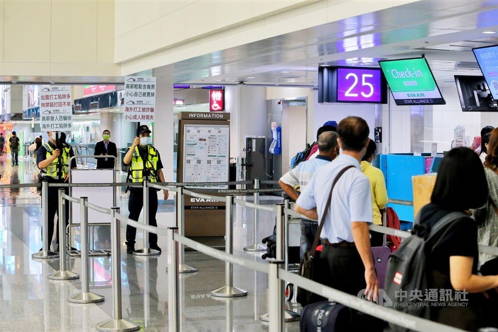 Policemen hold signs to warn passengers planning to travel to Cambodia about job scams reportedly linked to the Southeast Asian country, at Taiwan Taoyuan International Airport in early August. CNA file photo