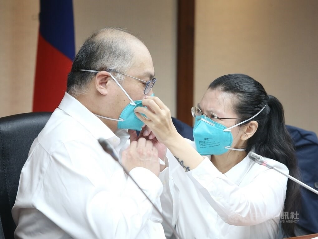 Lee Ching-yu (李凈瑜, right) adjusts the face mask her husband Lee Ming-che (李明哲) was wearing during a news conference in Taipei on May 10, following his release by China in April. He had been detained by Chinese authorities since March 2017 when he was taken into custody while traveling from Macau to China.