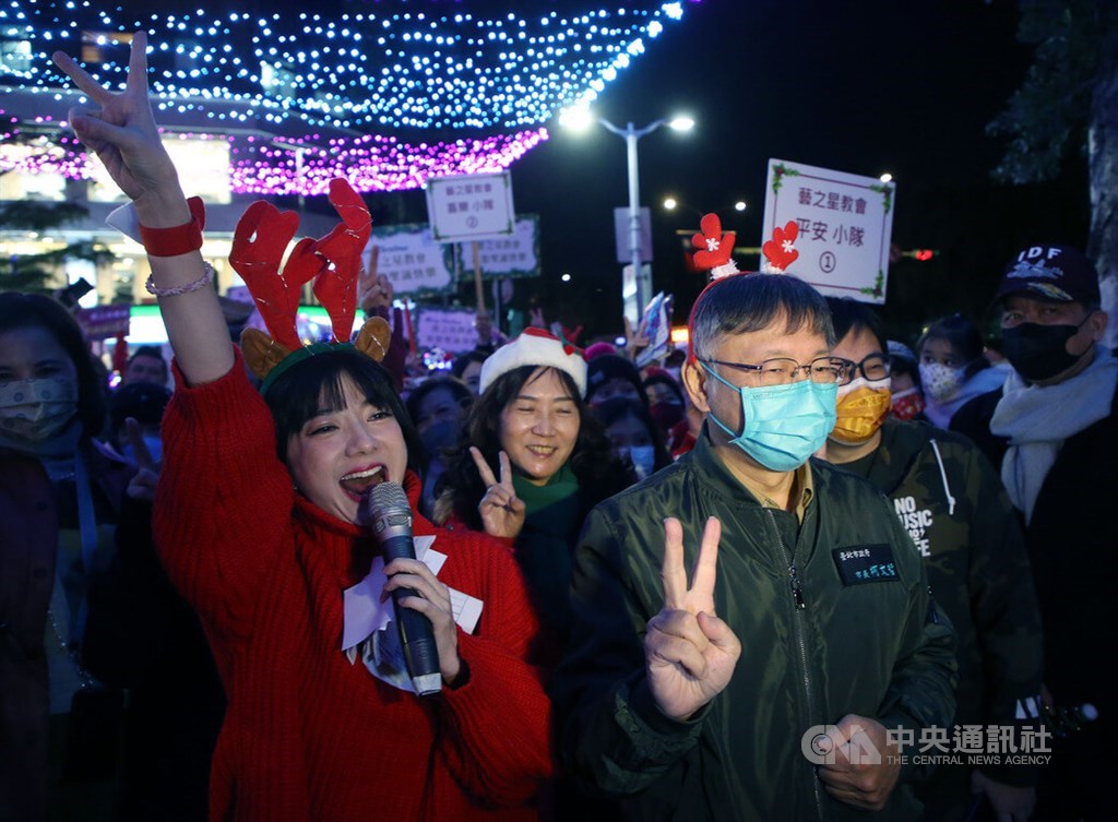 Former Taipei Mayor Ko Wen-je (柯文哲, front right) makes a V sign when joining Christmas carolers in Taipei on Dec. 23, his last working day as mayor. He returned to his job as a physician and researcher at National Taiwan University Hospital on Dec. 26.