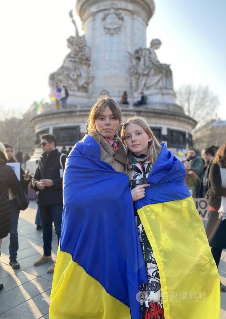 Ukrainian teenager Mariia (left), 15, and her 11-year-old sister wrap themselves in the national flag of Ukraine at a rally held in Paris on March 5, after they fled their home country following the Russian invasion of Ukraine on Feb. 24.
