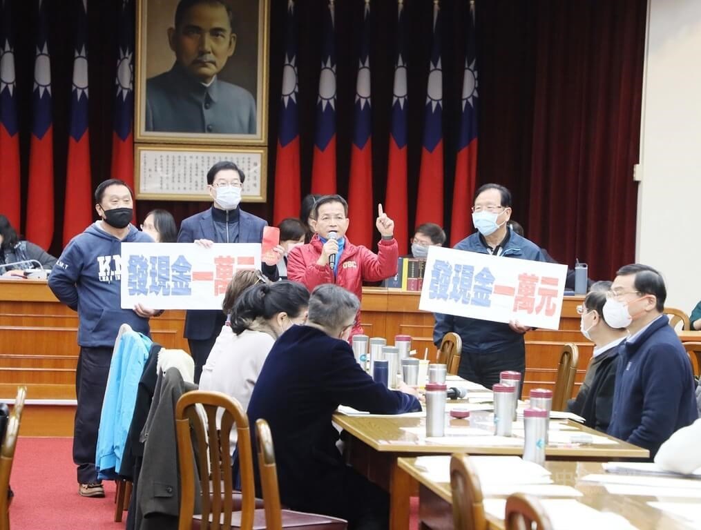 KMT lawmakers hold signs of their proposed amount of NT$10,000 in the government