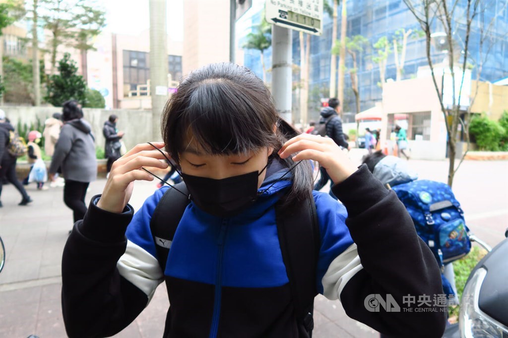 A student puts on her face mask before entering the school in Taipei on Monday, as the mask mandate remains in places in all schools before March 6. CNA photo Feb. 20, 2023
