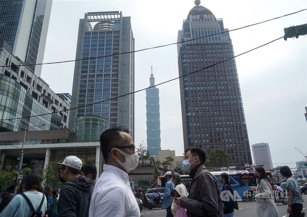 Pedestrians, many still wearing a face mask, walk across a road in Taipei