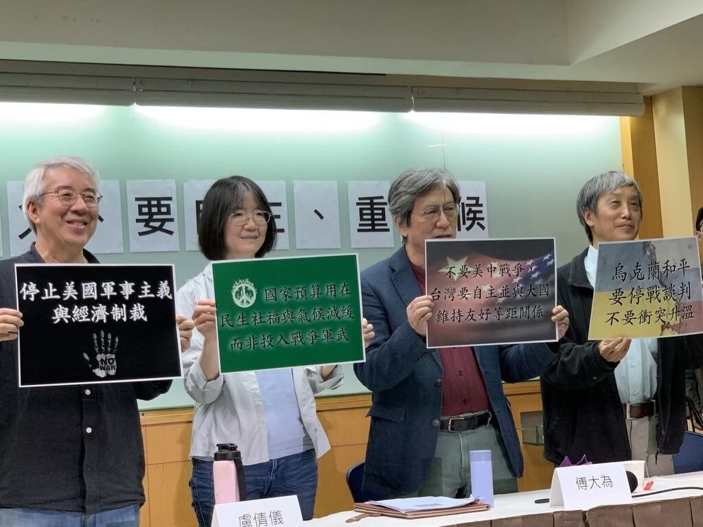 Scholars Kuo Li-hsin (from left), Lu Chien-yi, Daiwei Fu and Feng Chien-san hold paper boards with slogans that call for peace at Tuesday