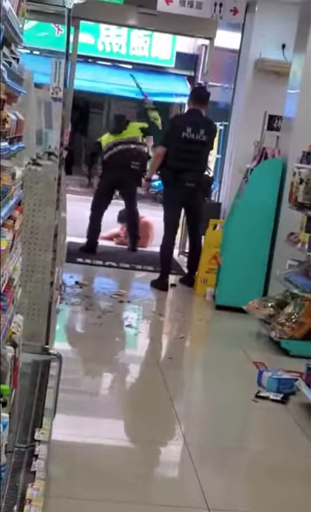 One of the policemen holds his baton high at the entrance of the store in Taoyaun