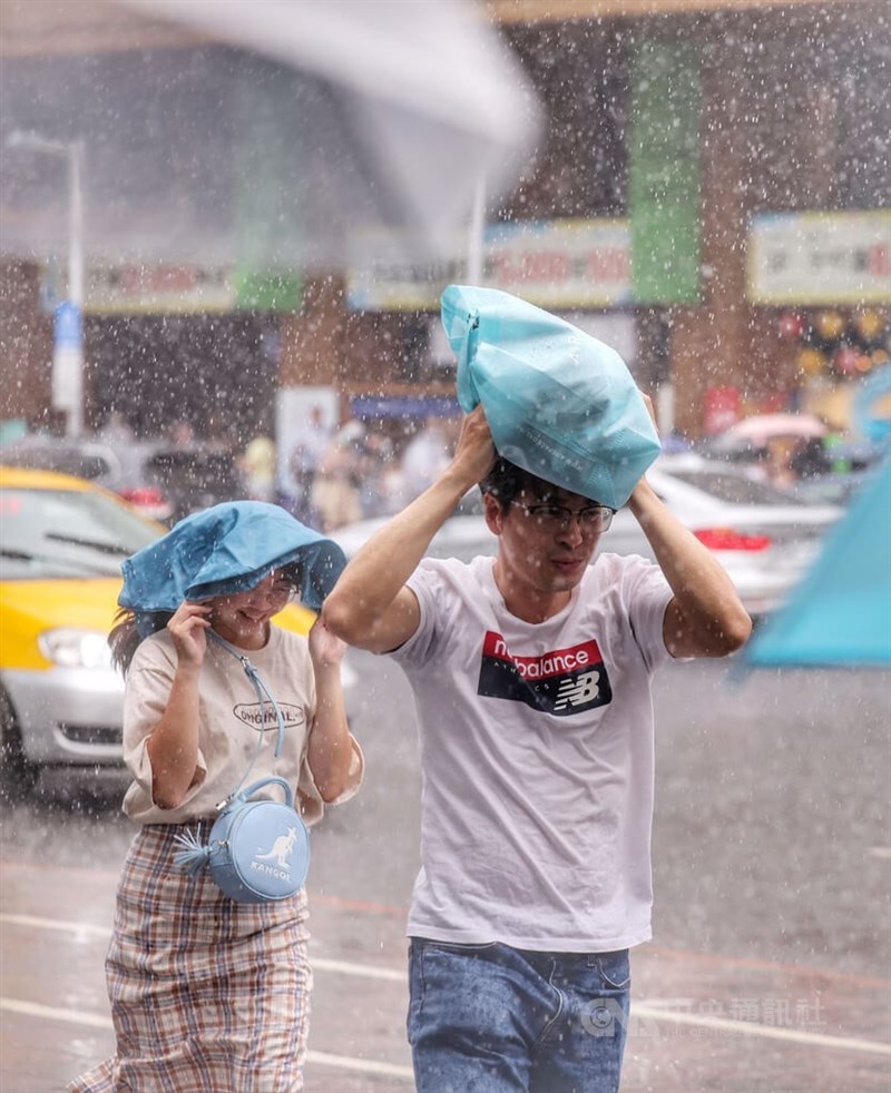 Pedestrians cover their head with bags and run in the rain in Taipei Sunday. CNA photo June 4, 2023