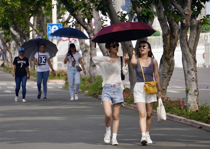 Walkers travel with umbrellas open to combat the high Thursday heat in Kaohsiung. CNA photo June 8, 2023